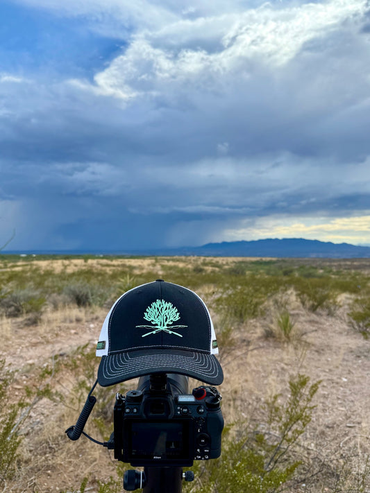 Signature Reef & Rods black and light blue trucker hat on a camera, storm sky