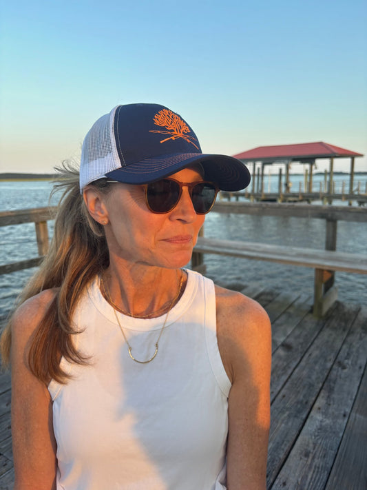 Signature Reef & Rods navy and orange trucker hat on a Key West dock