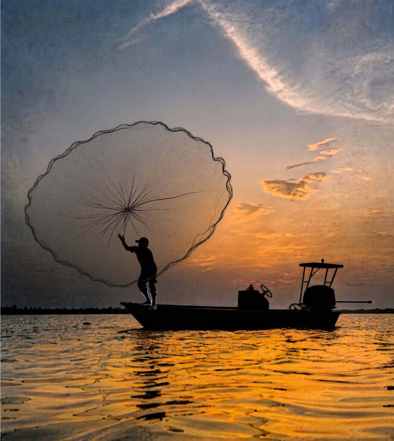 Fisherman on a skiff throwing a cast net at sunset